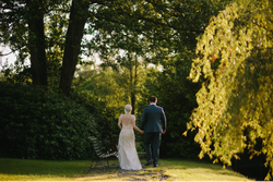 Bride and groom walking through grass path