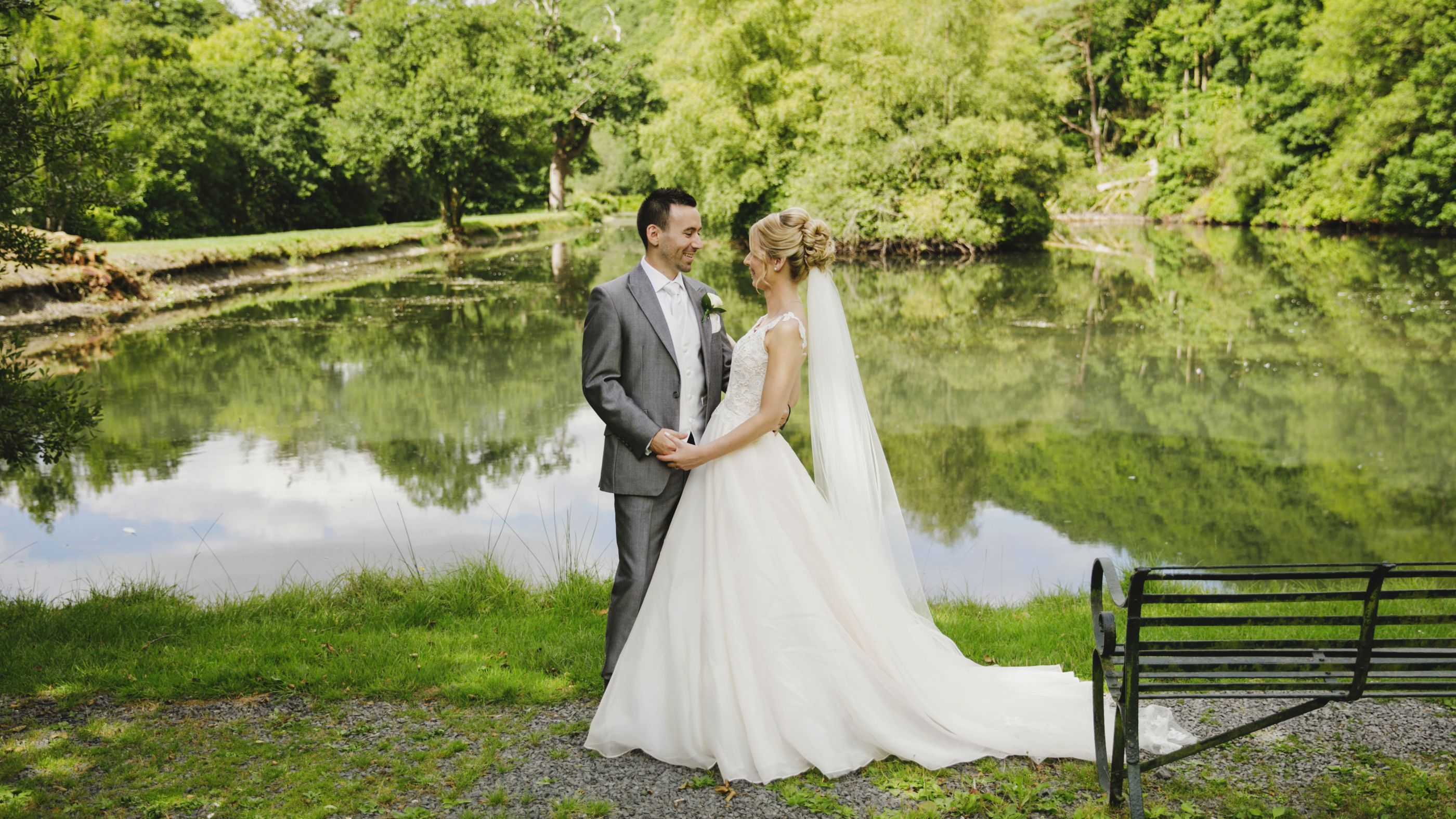 Bride and Groom posed next to a lake with trees behind
