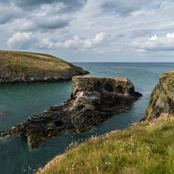 Welsh coastline with grassy rocks and blue sea