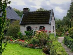 Small white cottage with blooming garden in front