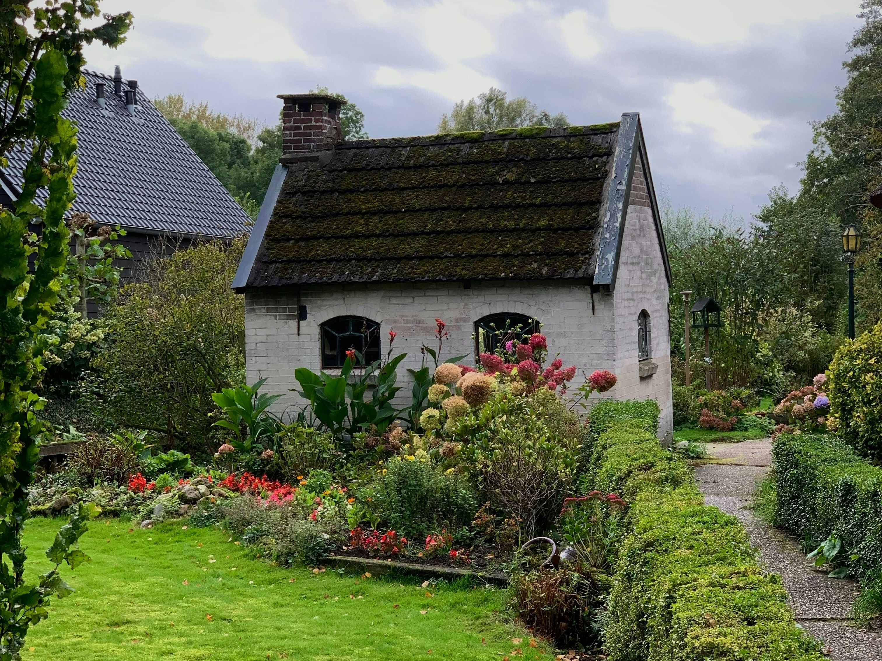 Small white cottage with blooming garden in front