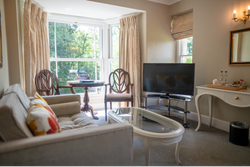 Bedroom seating area with sofa and wooden chairs around glass table