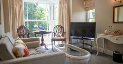 Bedroom seating area with sofa and wooden chairs around glass table