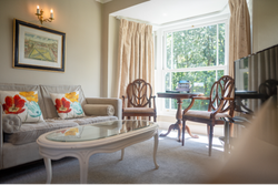 Bedroom seating area with sofa and wooden chairs around glass table