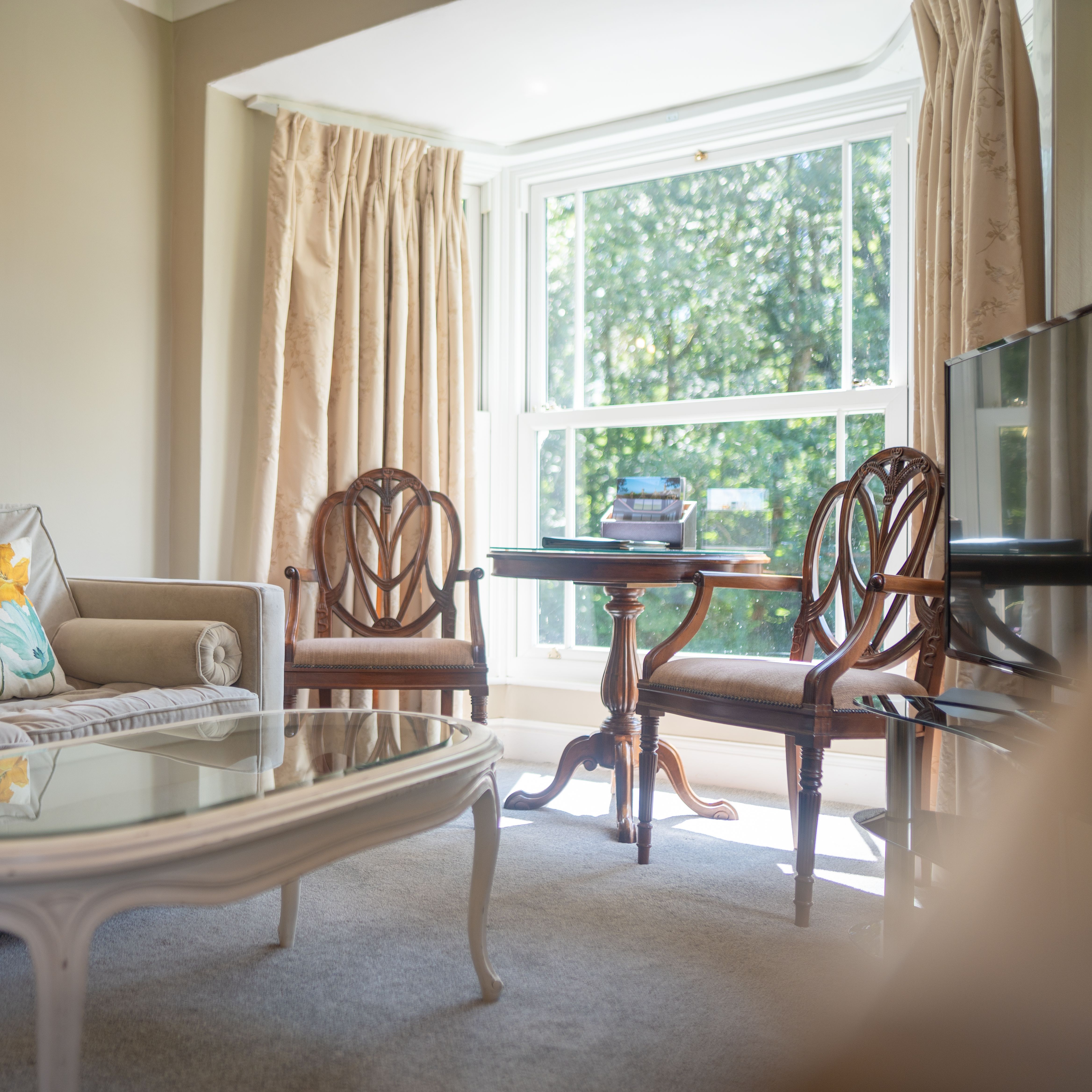 Bedroom seating area with sofa and wooden chairs around glass table