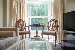Bedroom seating area with sofa and wooden chairs around glass table