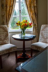Bedroom seating Area in front of window with a bouquet of flowers on the table