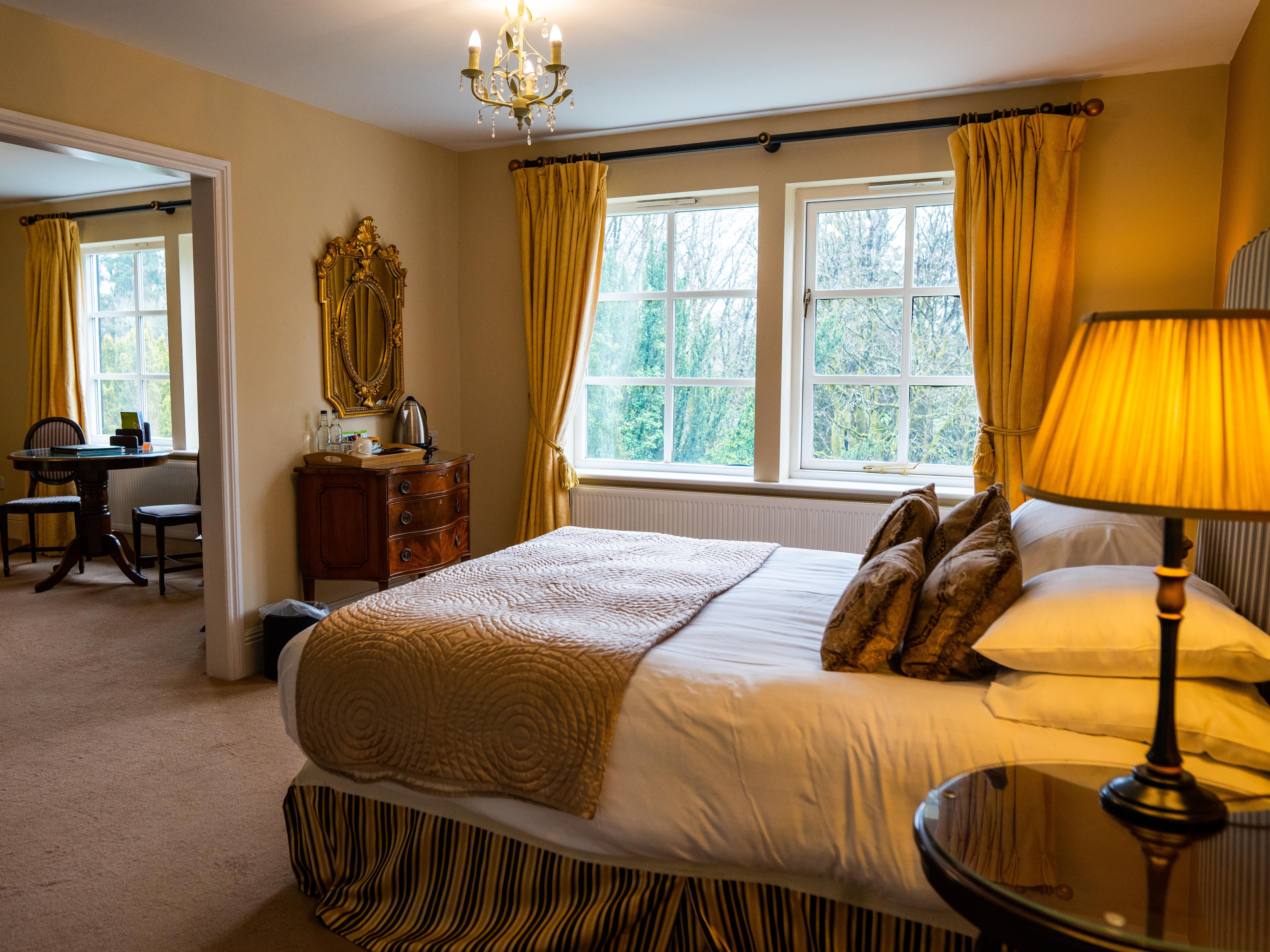 Double bed with gold theme looking onto sitting area in room