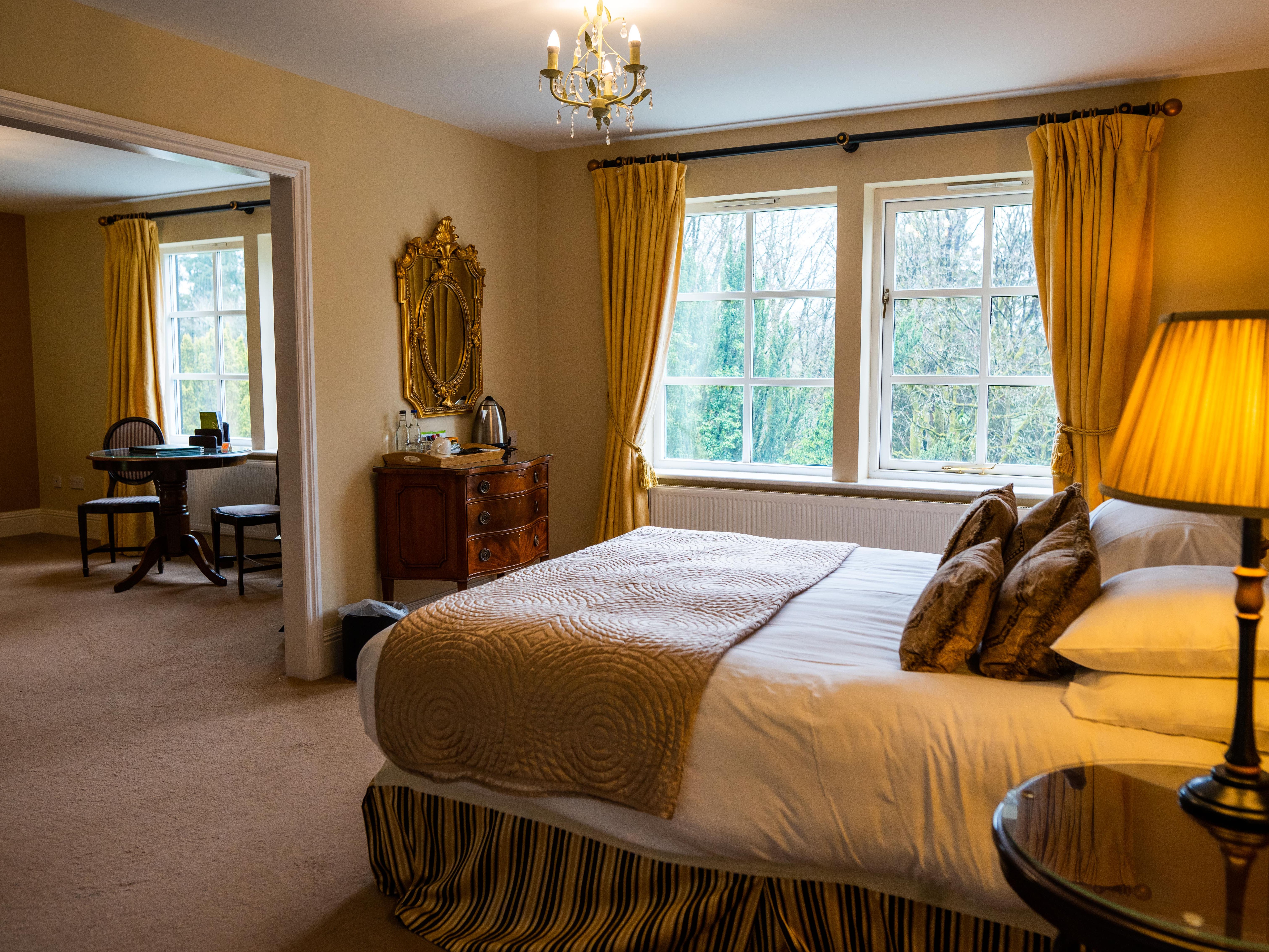 Double bed with gold theme looking onto sitting area in room