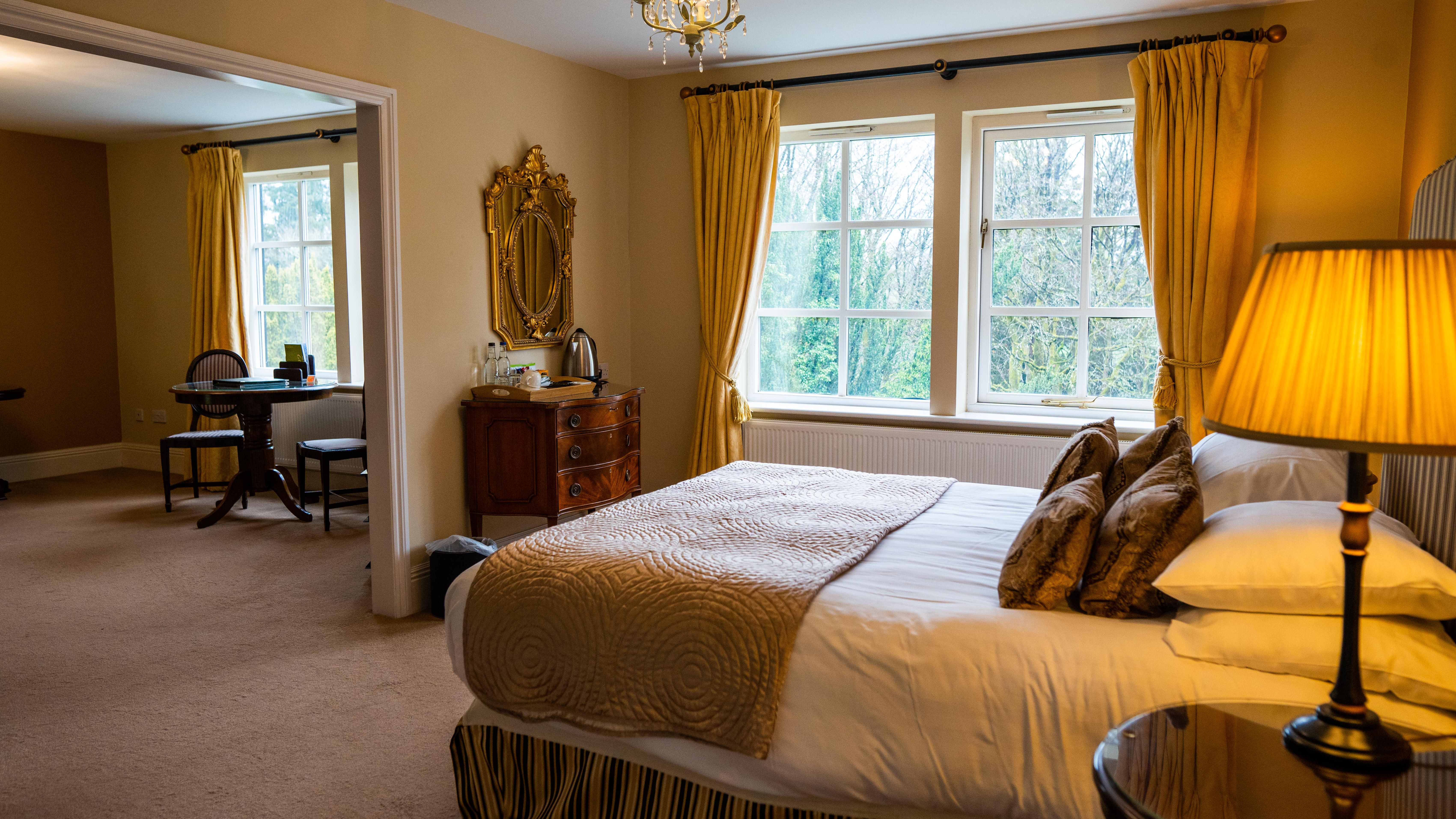 Double bed with gold theme looking onto sitting area in room