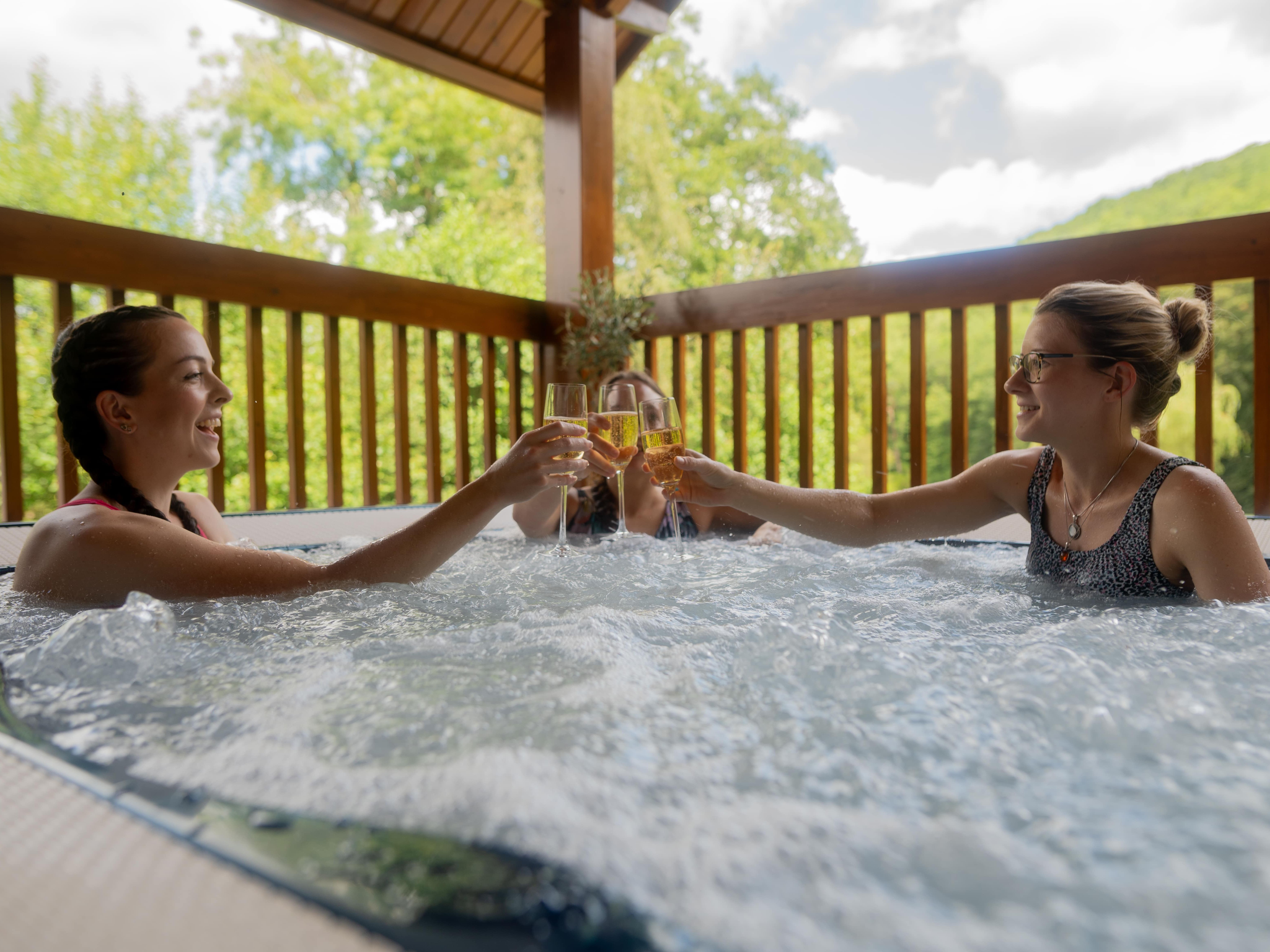 Group smiling in hot tub with glass of fizzy