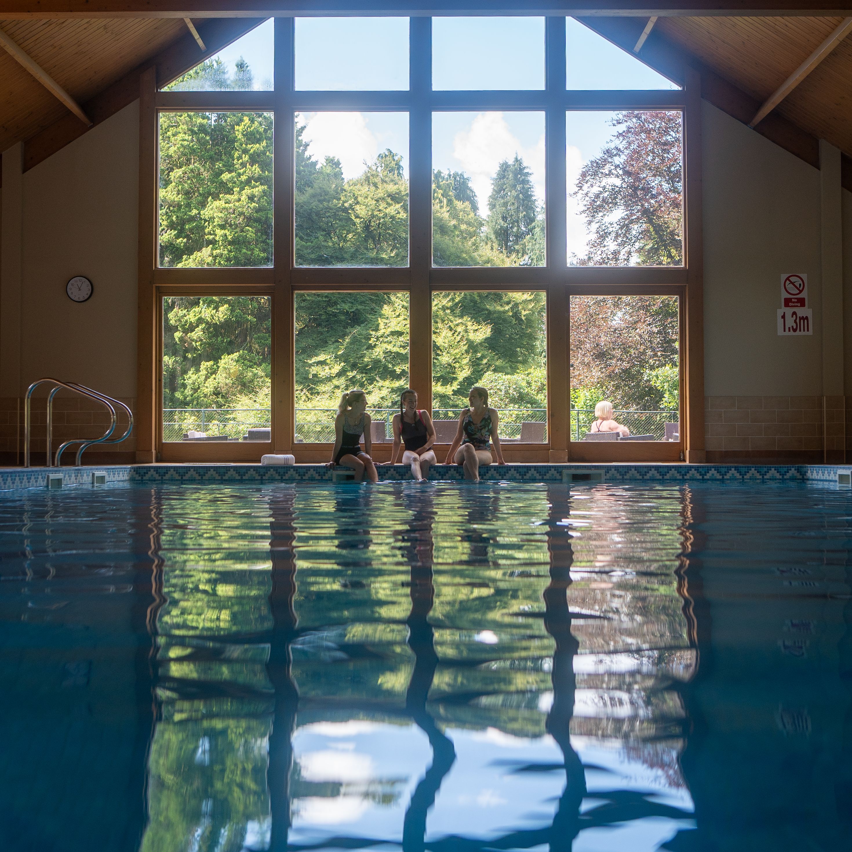 three women sat on the side of a pool
