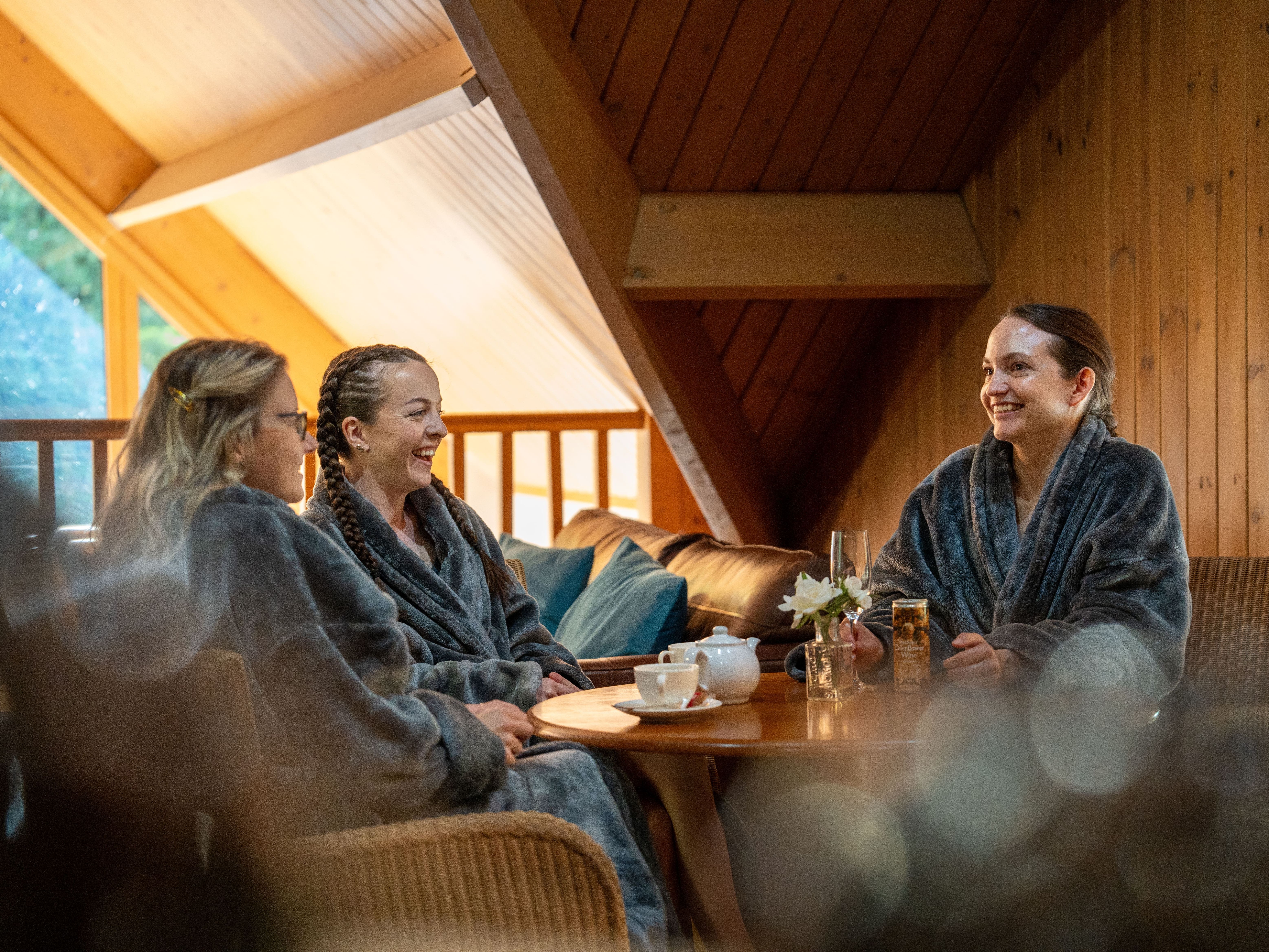 Group of ladies sharing a bottle of wine in spa gowns
