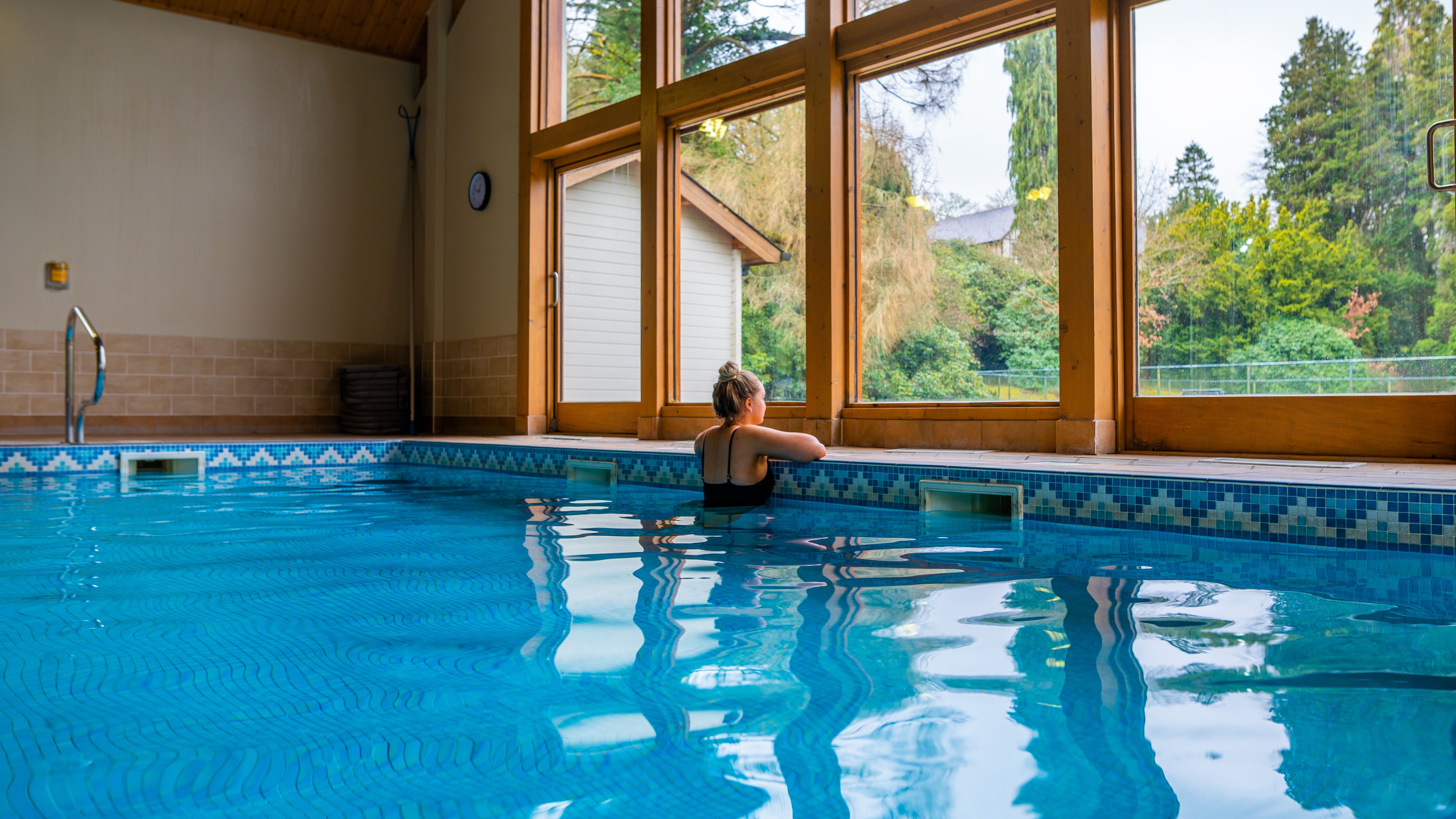 Lady in swimming pool looking out onto the green forest