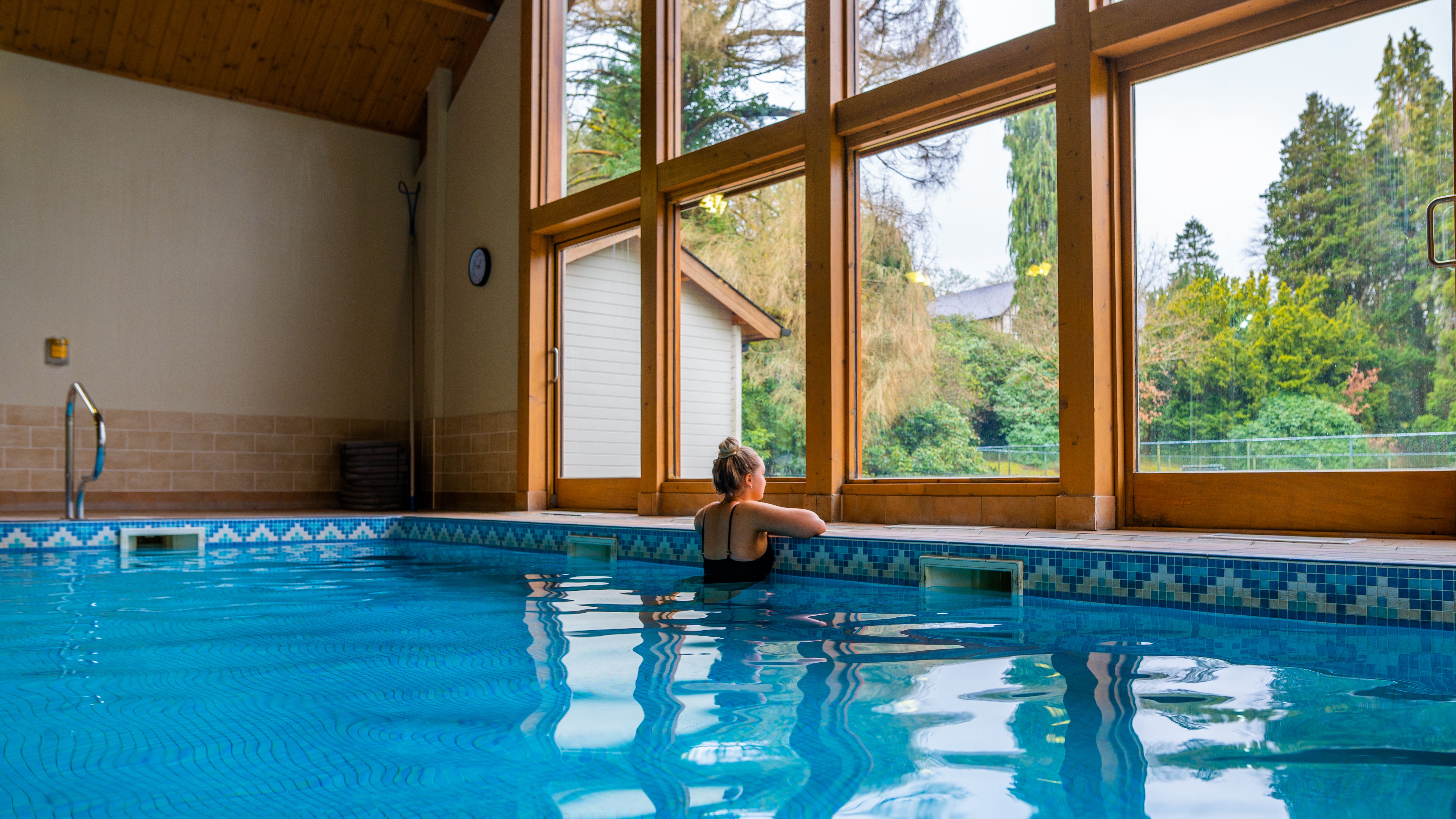 Lady in swimming pool looking out onto the green forest