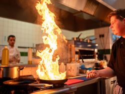 Chef using a flame lit frying pan