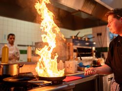 Chef using a flame lit frying pan