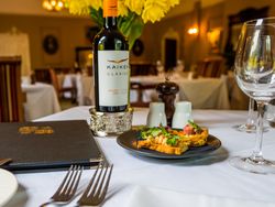 Table with plate of food and bottle of wine