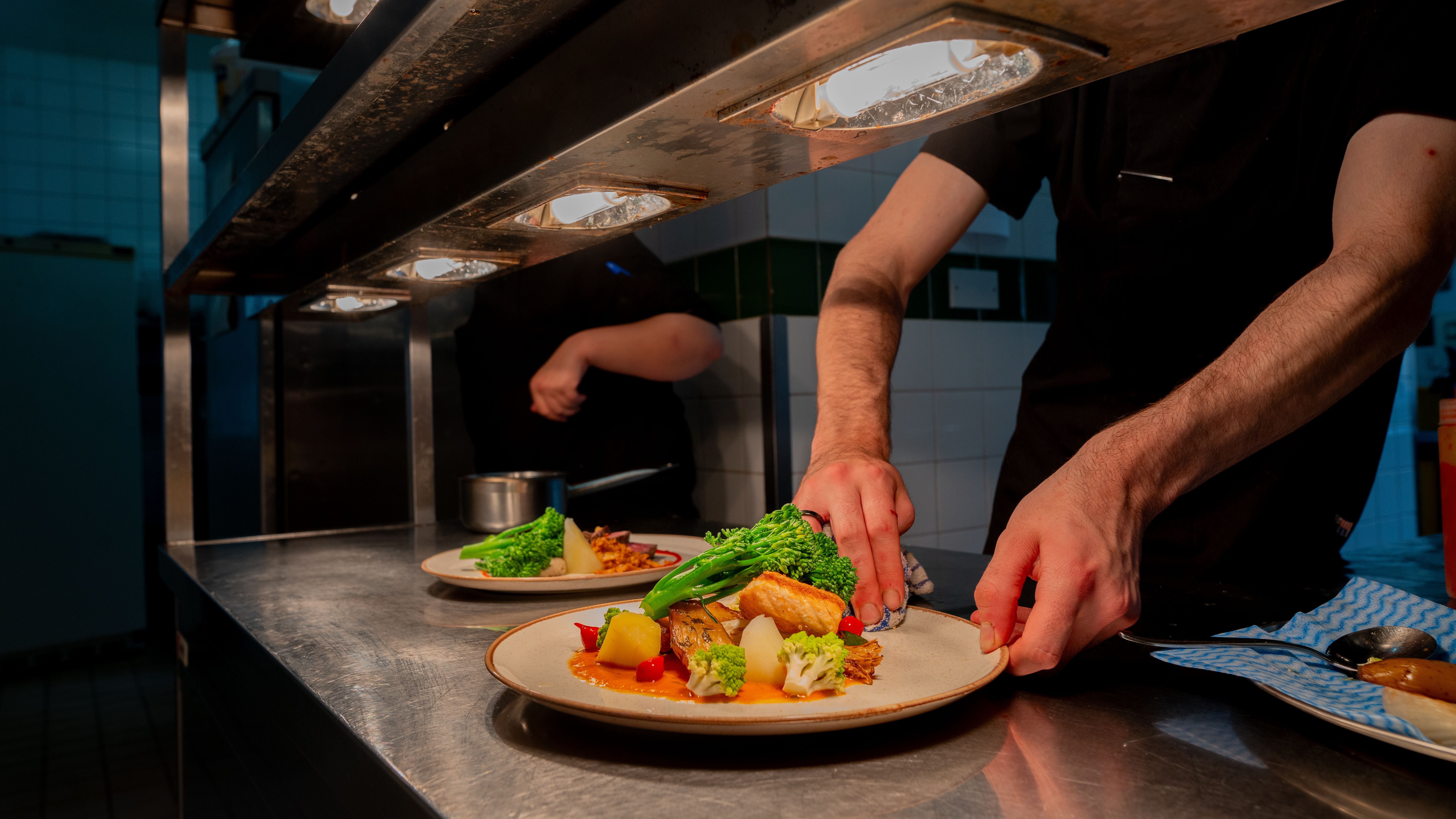 Plate of food under heat lamps in kitchen