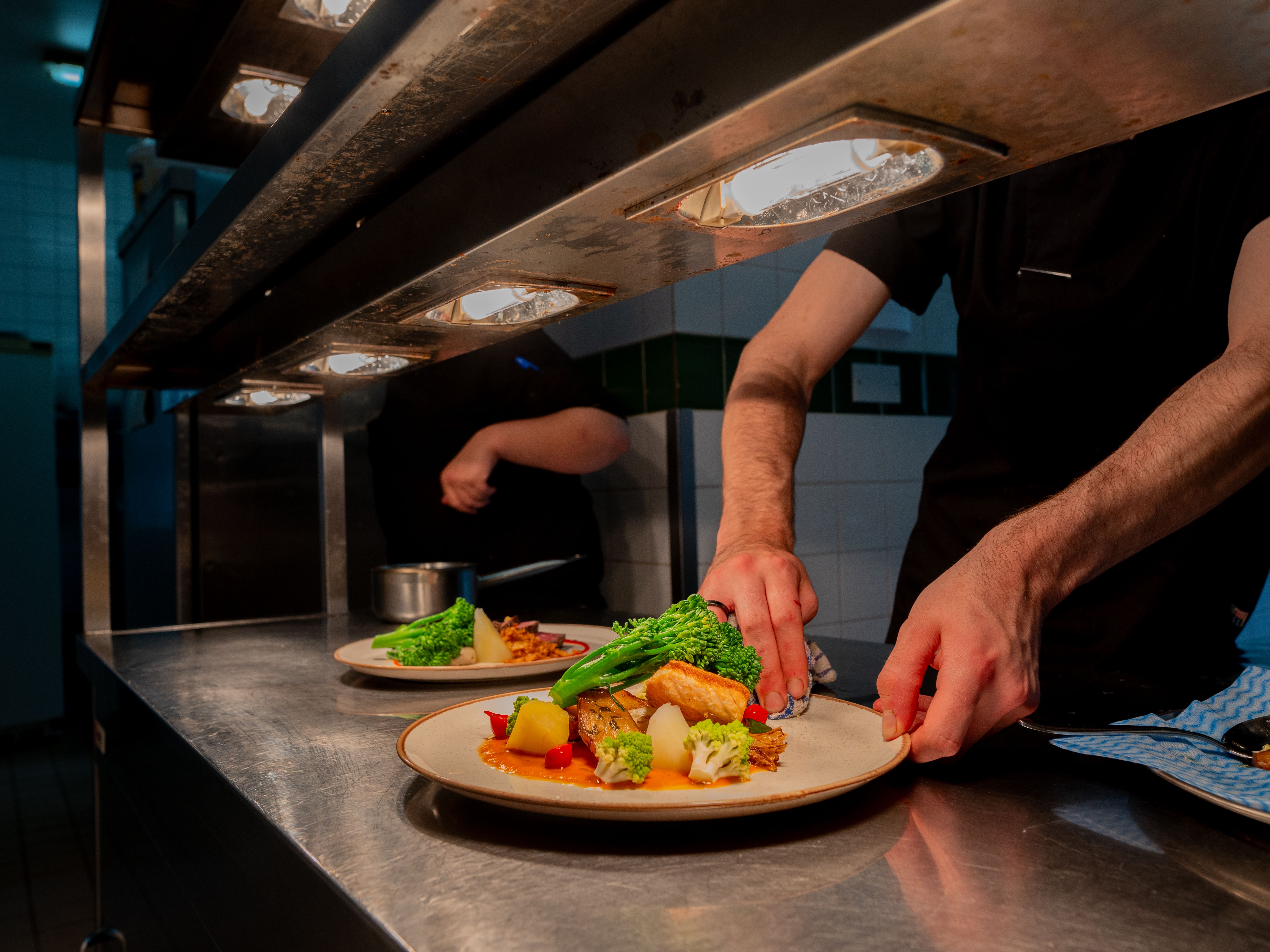 Plate of food under heat lamps in kitchen