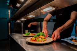 Plate of food under heat lamps in kitchen