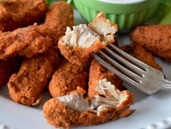 A plate of chicken strips and celery with a bowl of sauce in the middle