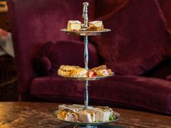 Three-tired silver stand filled with cakes and sandwiches