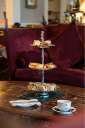 Three-tired silver stand filled with cakes and sandwiches