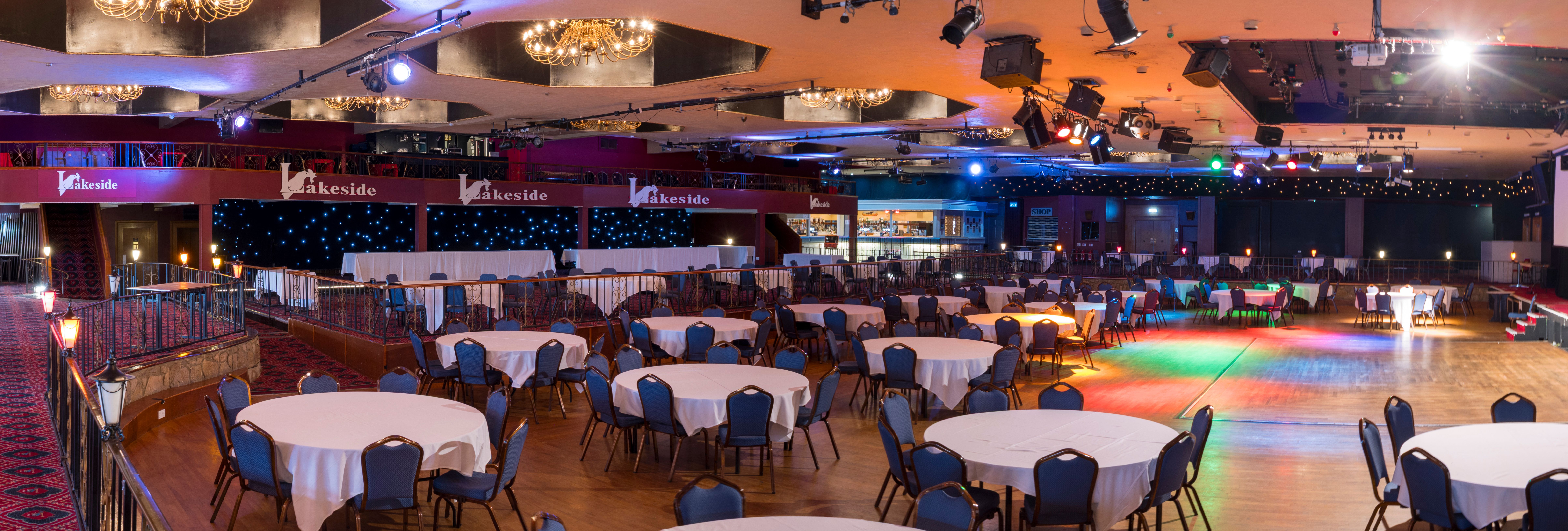 Lakeside event venue with round tables and stage, ready for a banquet or performance.