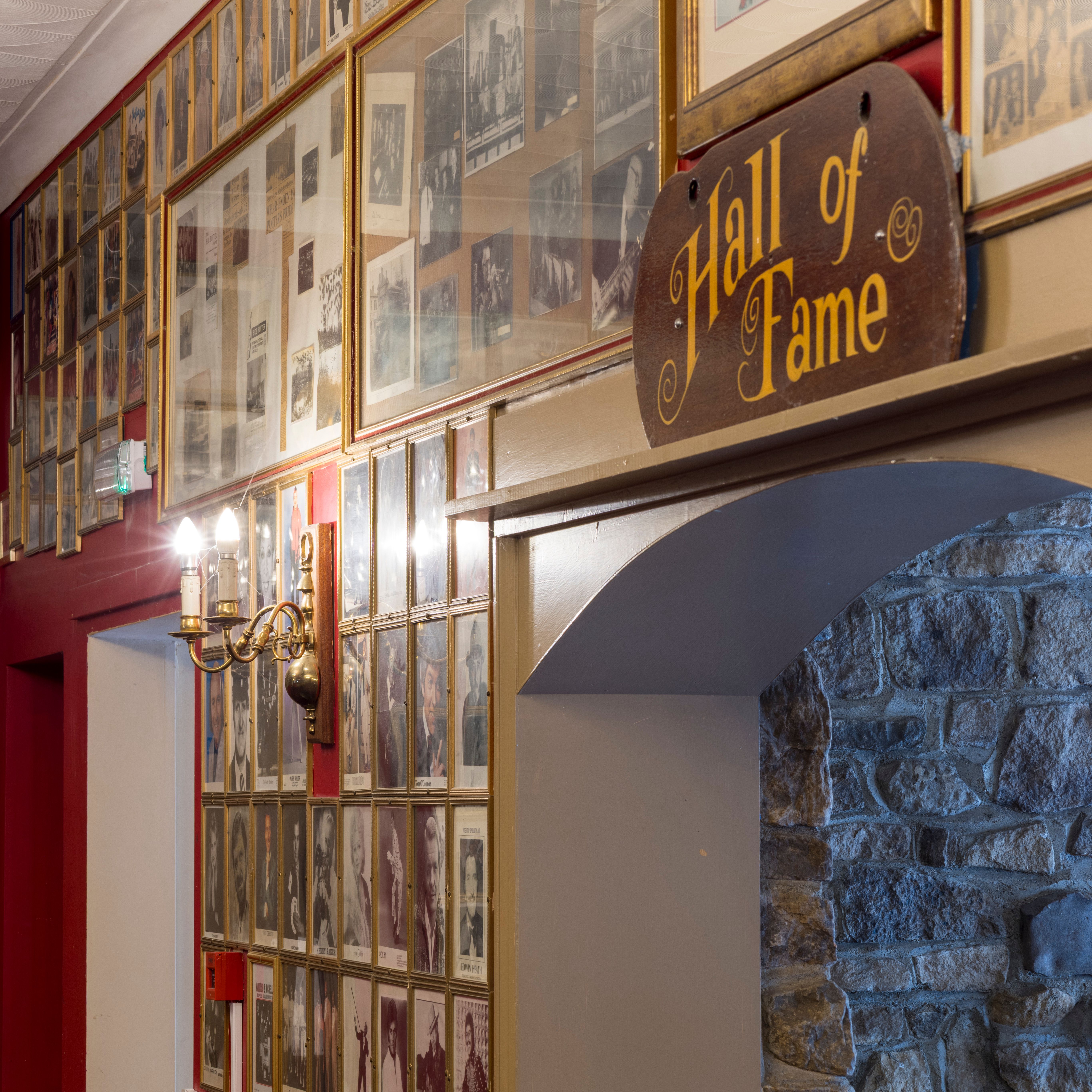 Framed photos and a wooden 'Hall of Fame' sign in a hallway