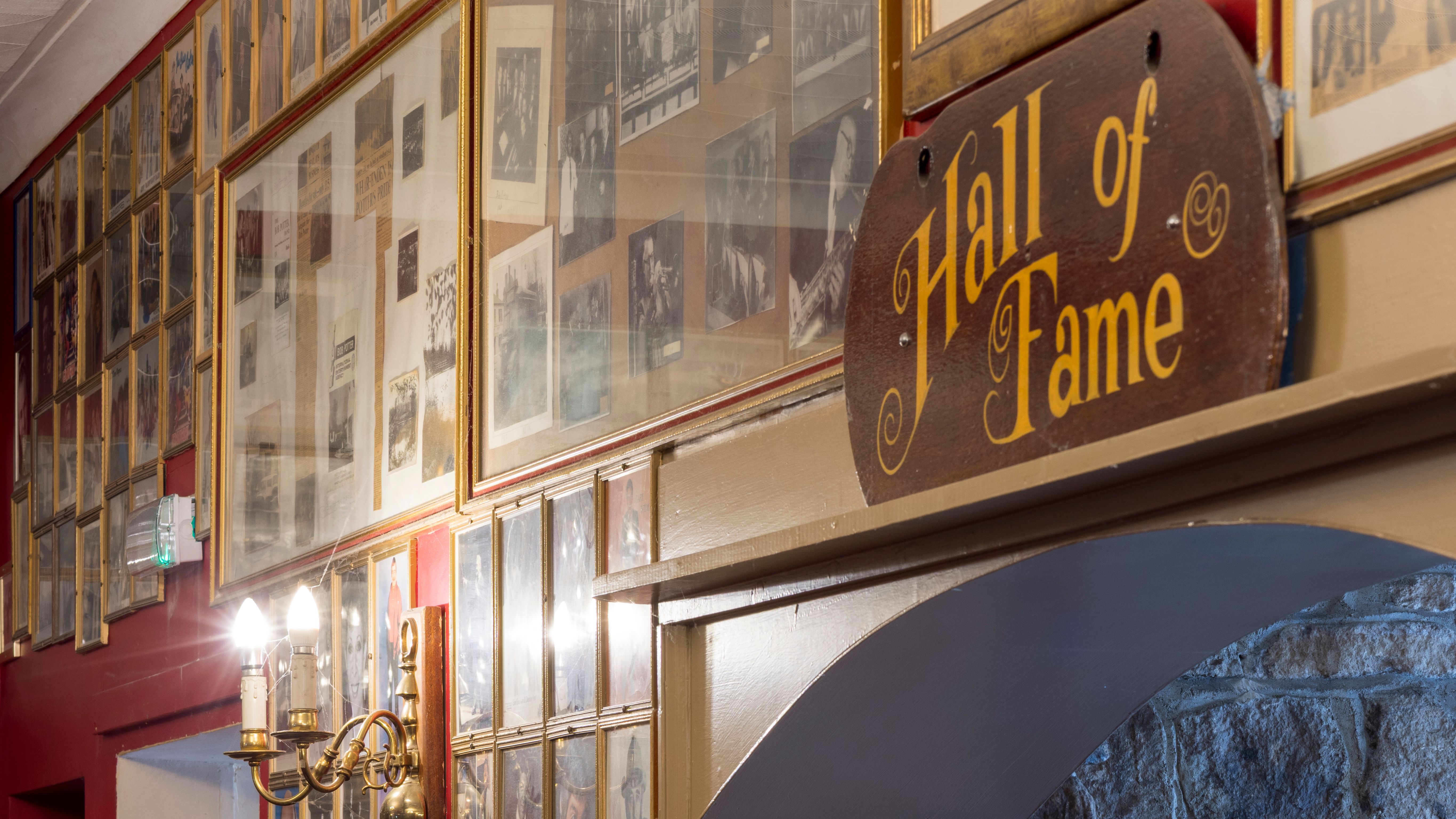 Framed photos and a wooden 'Hall of Fame' sign in a hallway