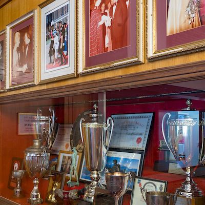Display case with trophies and framed photographs on the wall above