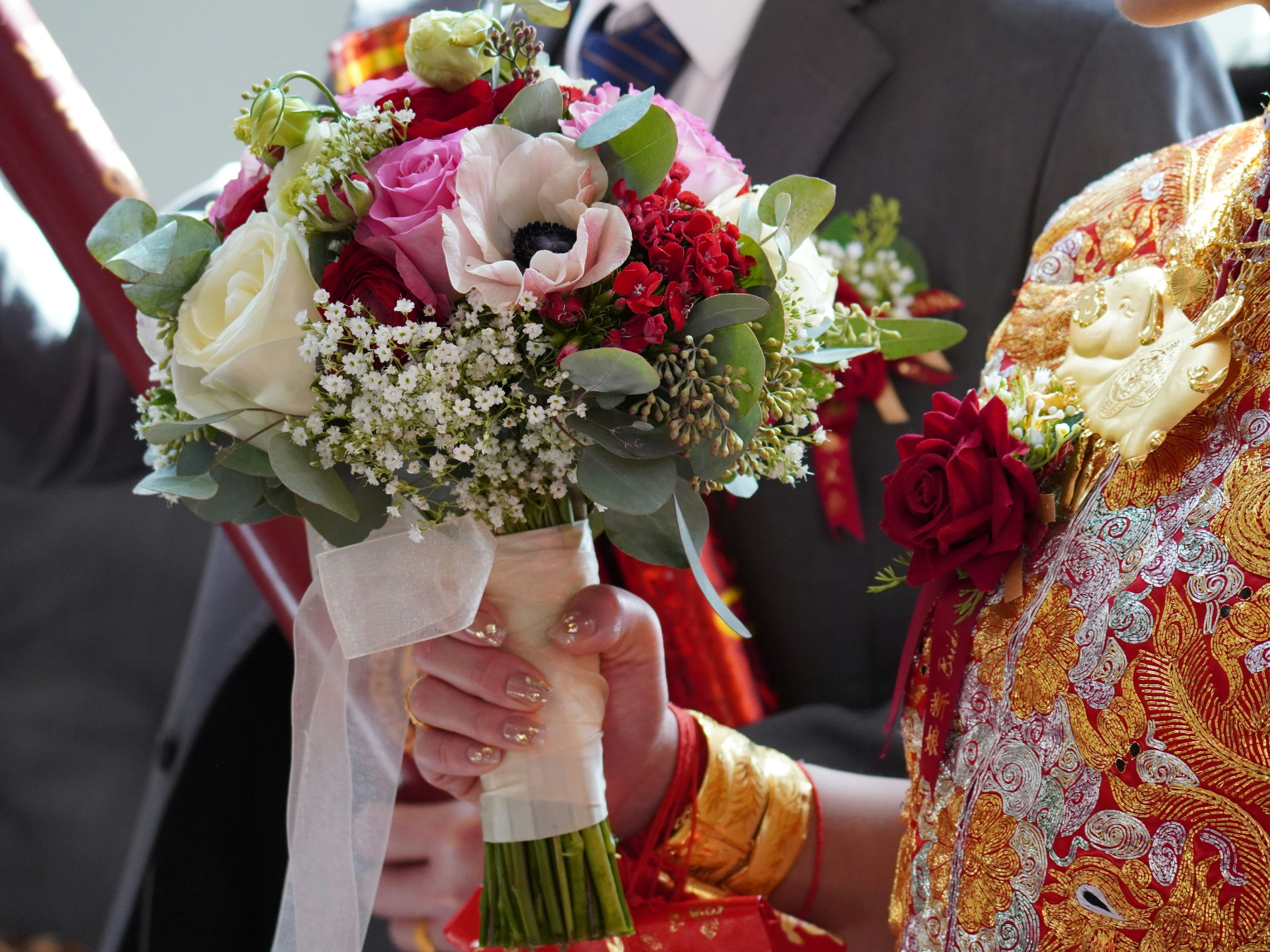 Bride holding a colorful bouquet of flowers during a traditional wedding ceremony