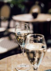 Two glasses of sparkling wine on an outdoor café table.