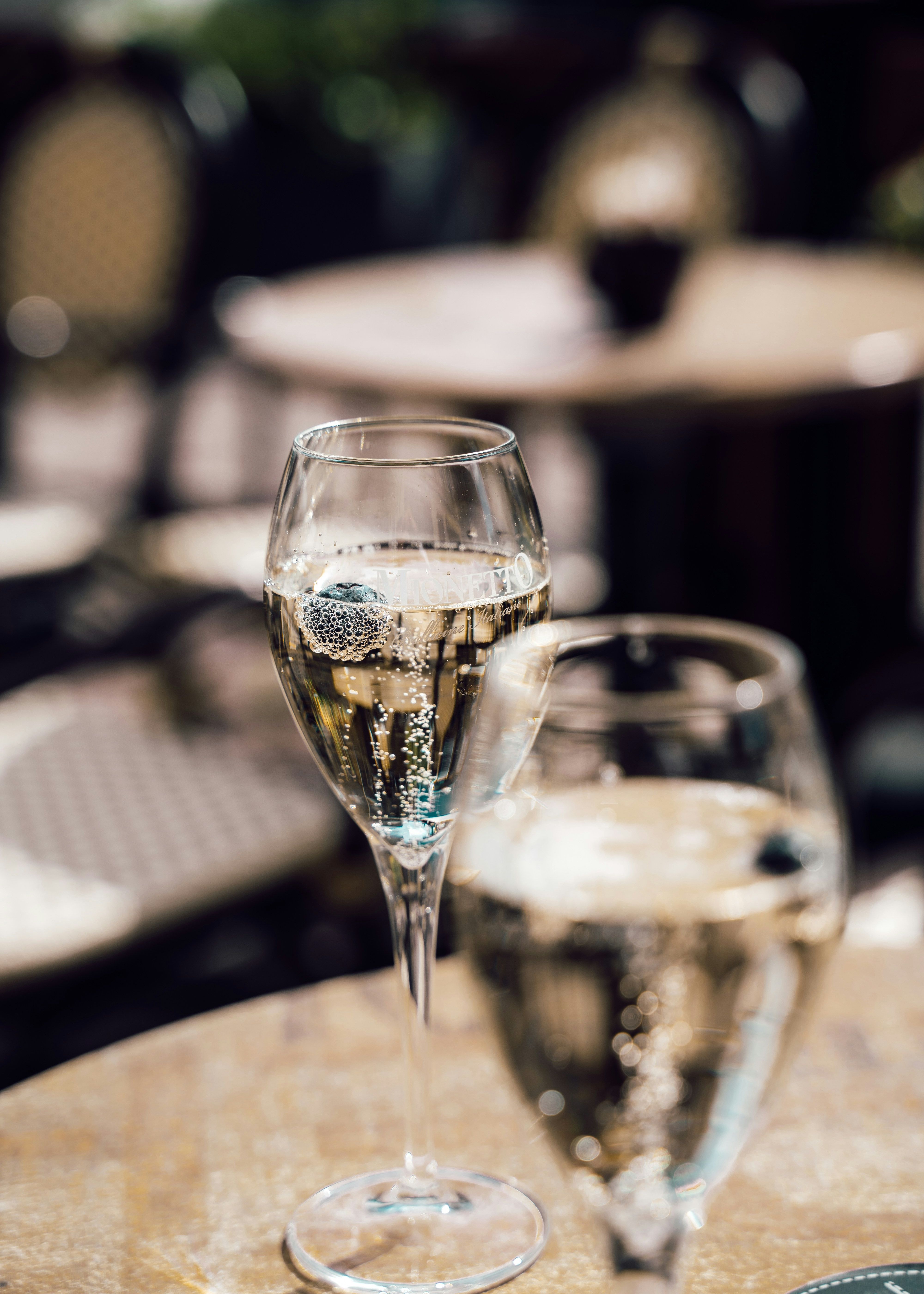 Two glasses of sparkling wine on an outdoor café table.