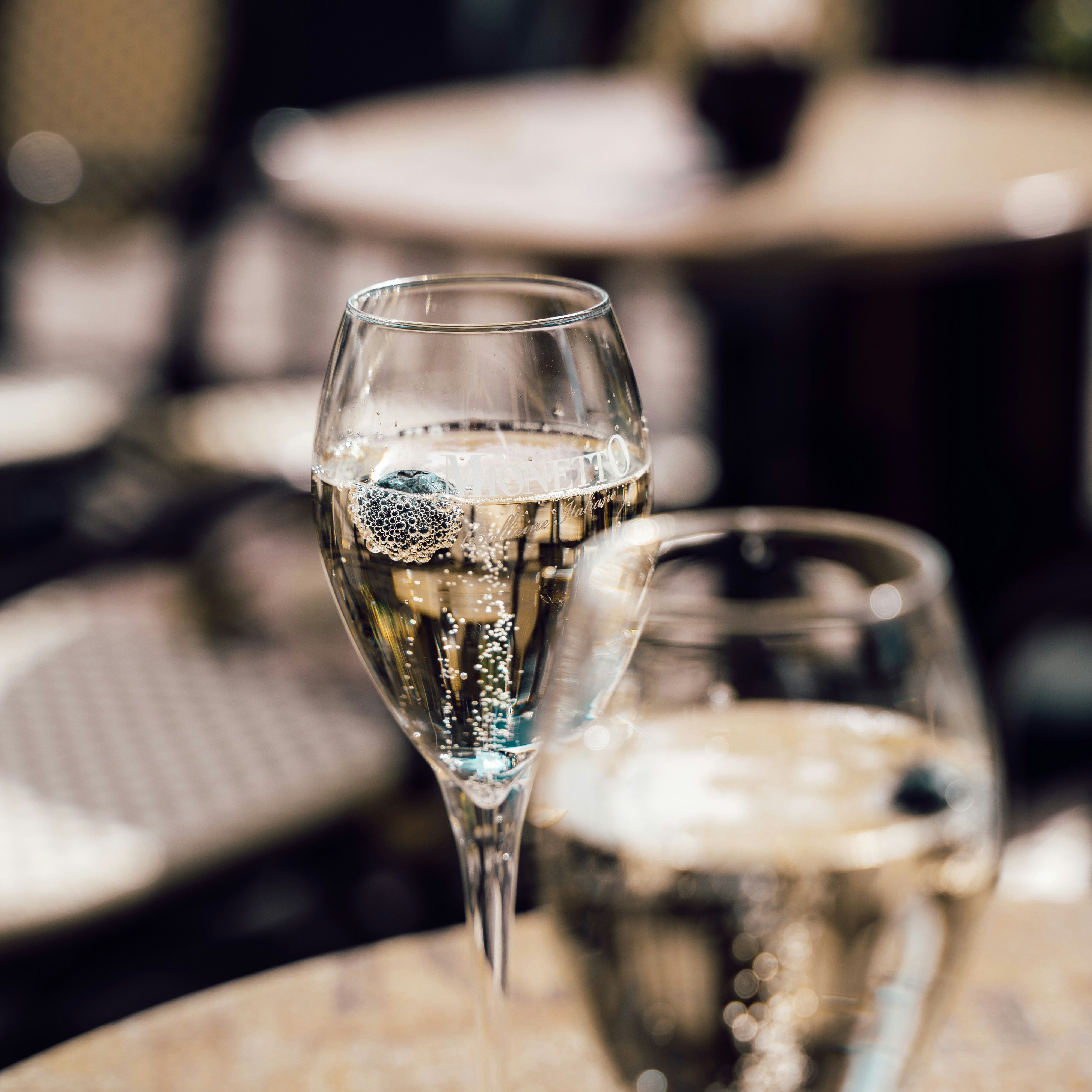 Two glasses of sparkling wine on an outdoor café table.
