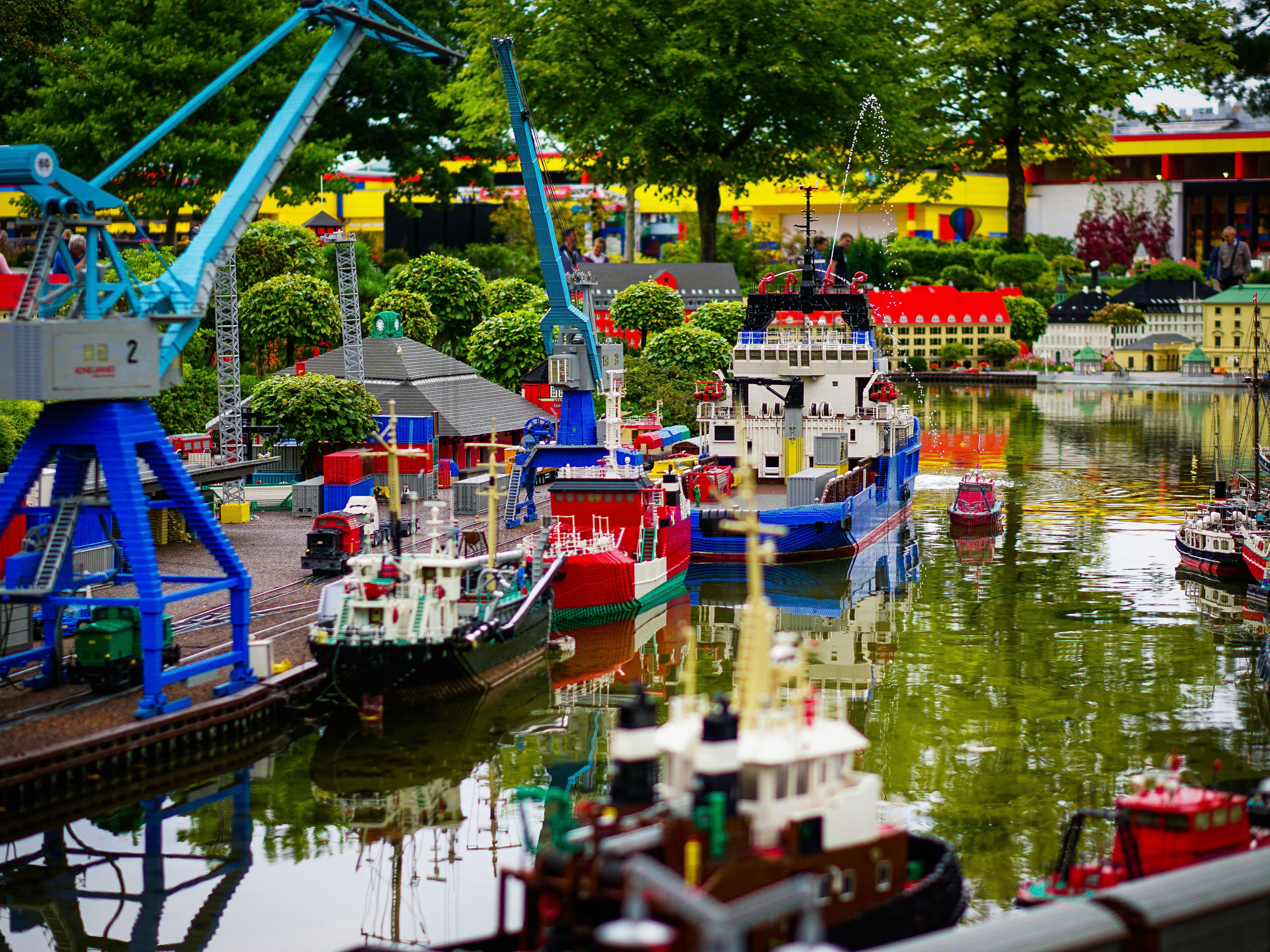 Miniature harbor scene built from LEGO bricks with ships, cranes, and buildings beside a waterway.