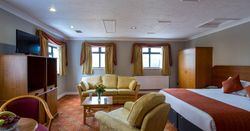 Spacious hotel suite with bed, sitting area, and large windows