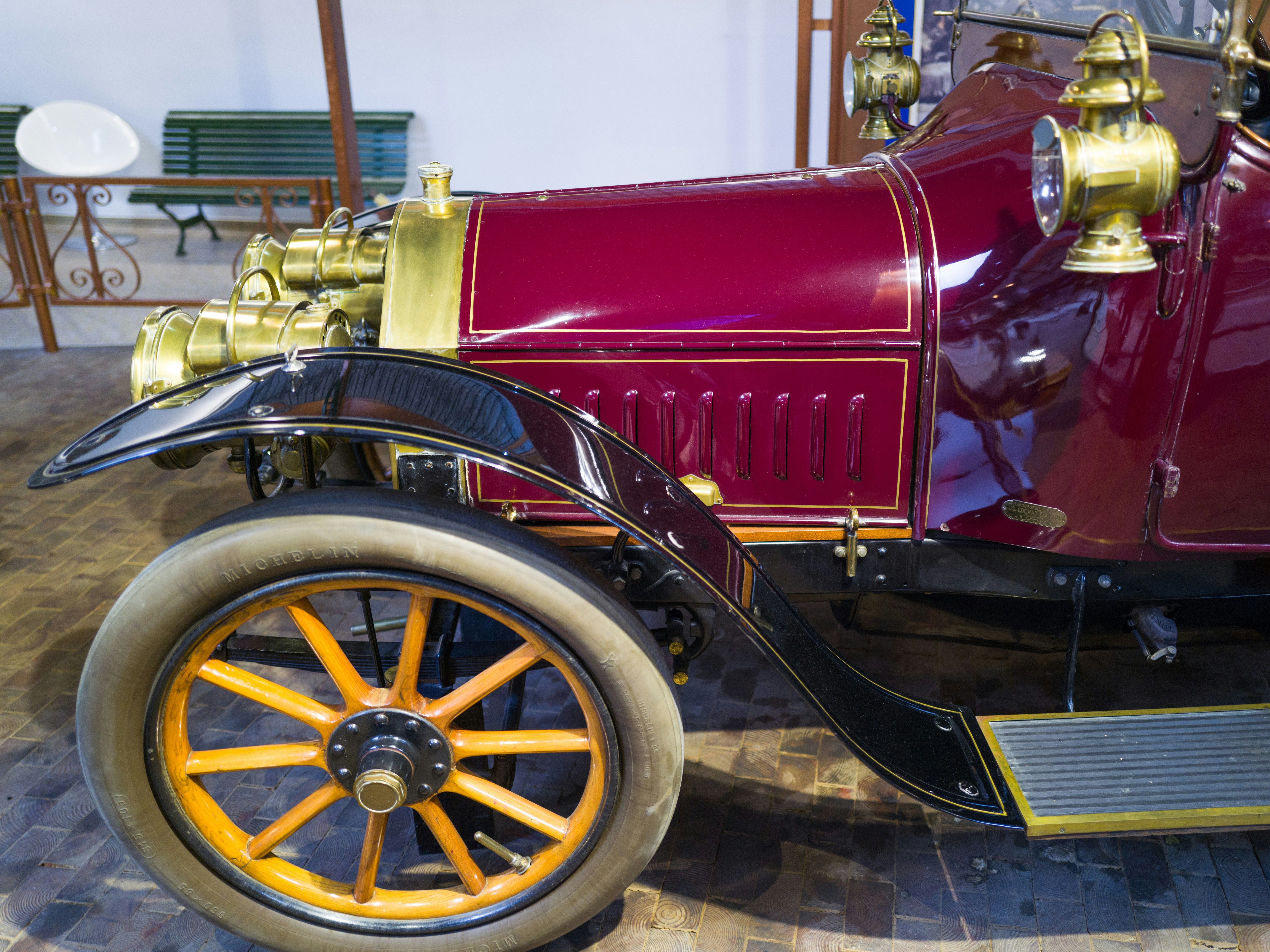 Close-up of a vintage red car with brass details and wooden-spoked wheels