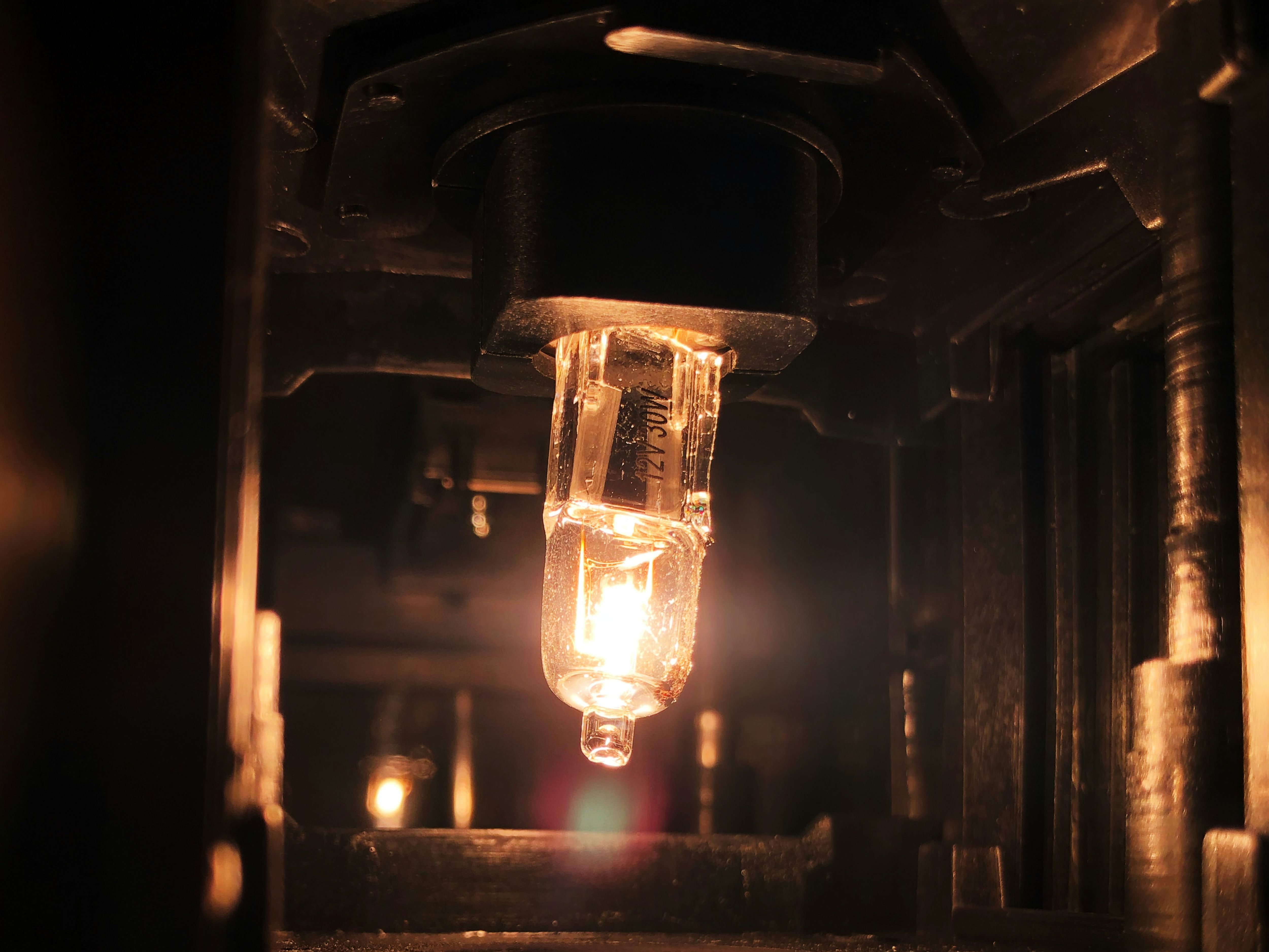 Close-up of a glowing light bulb inside a mechanical or industrial fixture