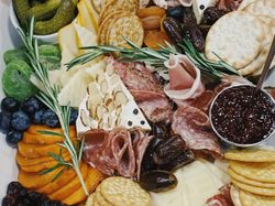 A charcuterie board with assorted crackers, cheeses, fruits, olives, nuts, and cured meats