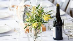 Elegant table setting with yellow flowers, wine bottle, and glassware
