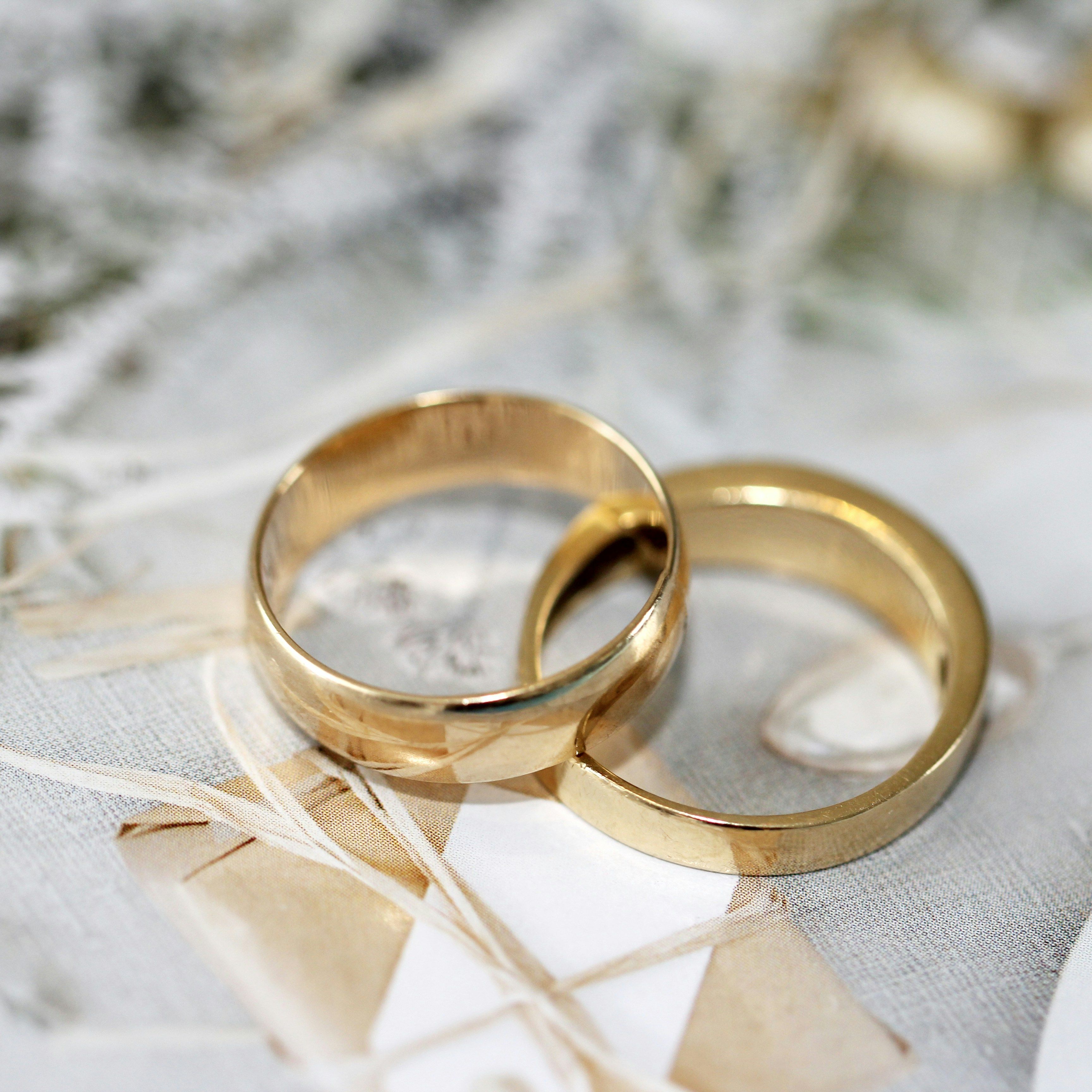 Two gold wedding rings placed on a decorative background
