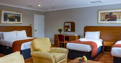 Hotel room with a double bed, two single beds, armchairs, and a desk
