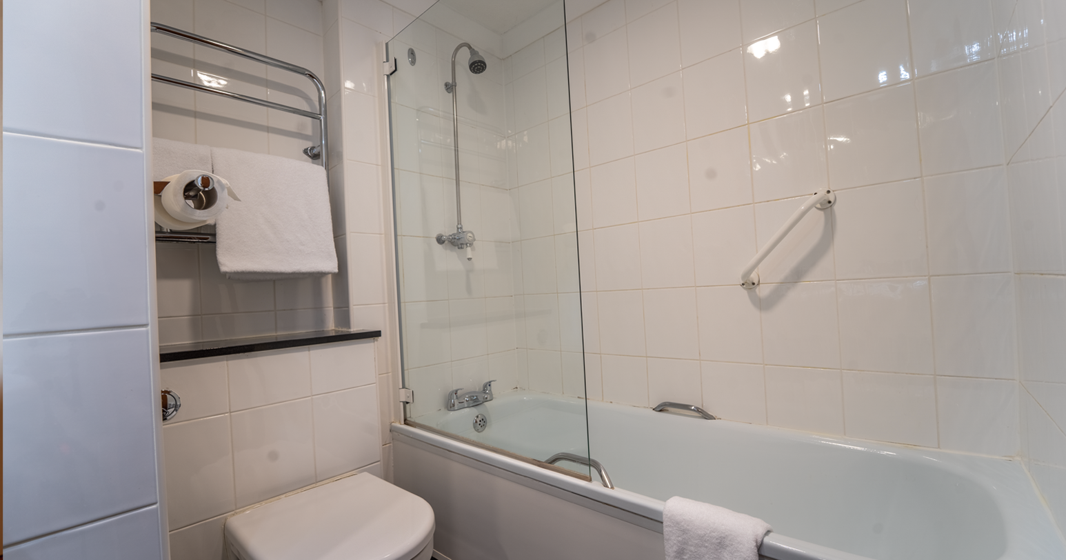 Modern bathroom with white tiles, a bathtub and a toilet
