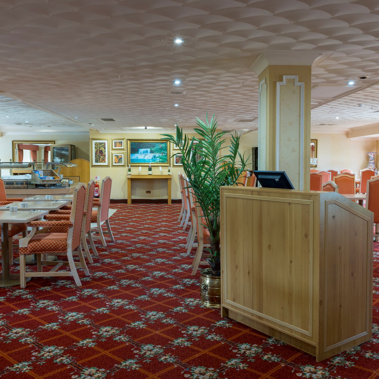 Empty dining area with orange chairs and patterned carpet