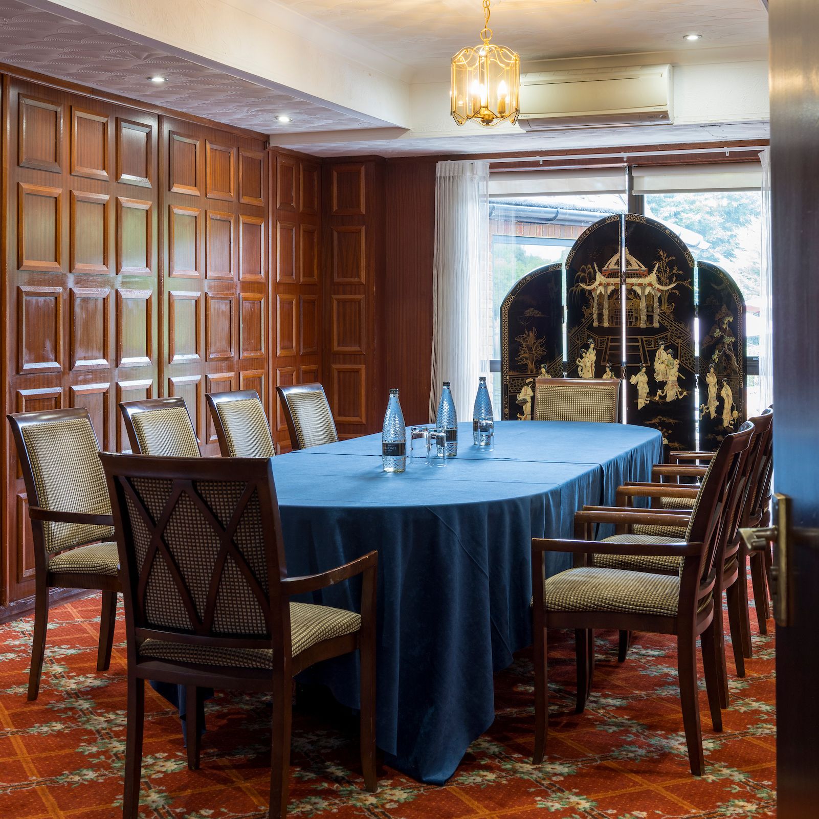 Elegant conference room with a blue tablecloth, wooden chairs, and decorative wall paneling.