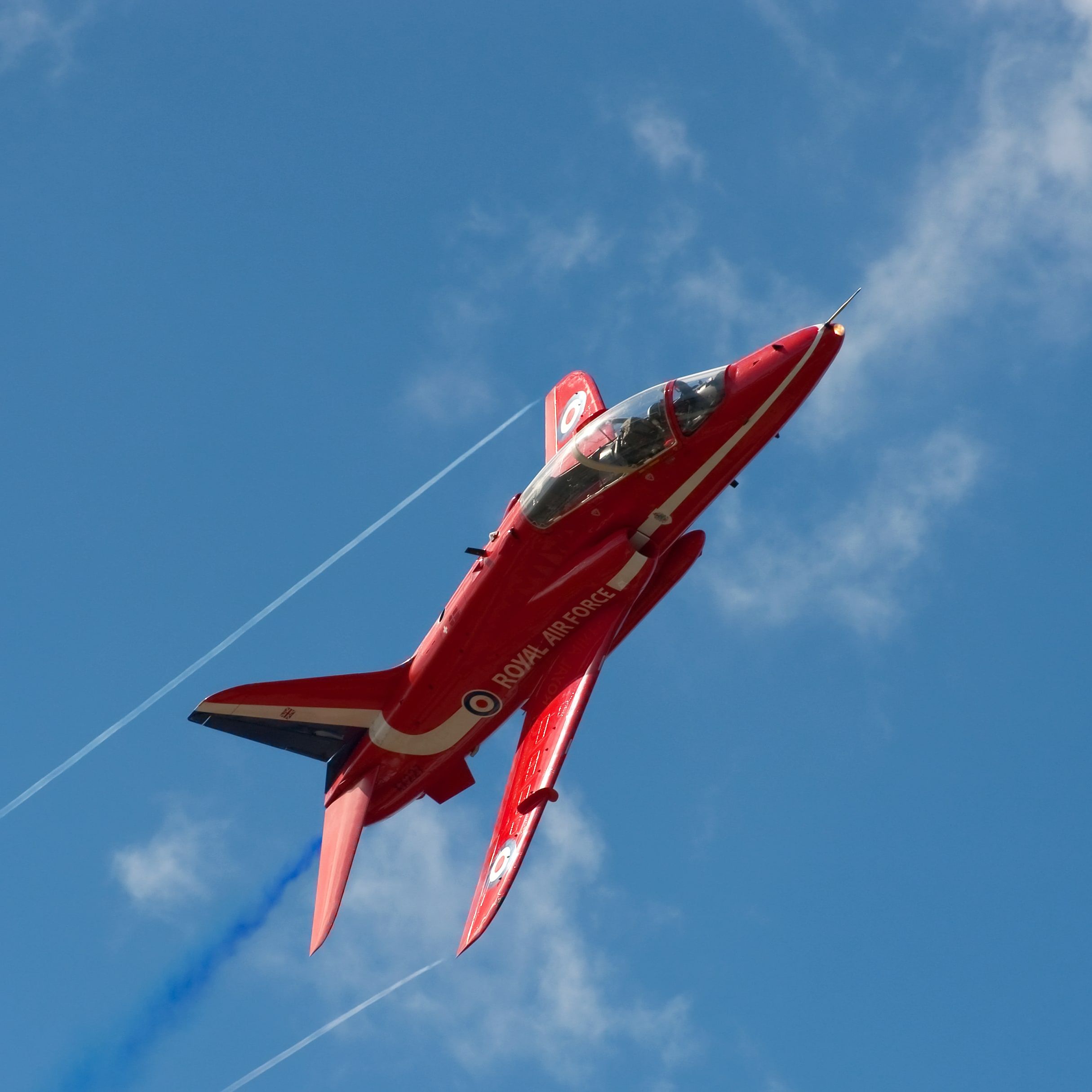 Red Royal Air Force jet performing aerial maneuver against a blue sky