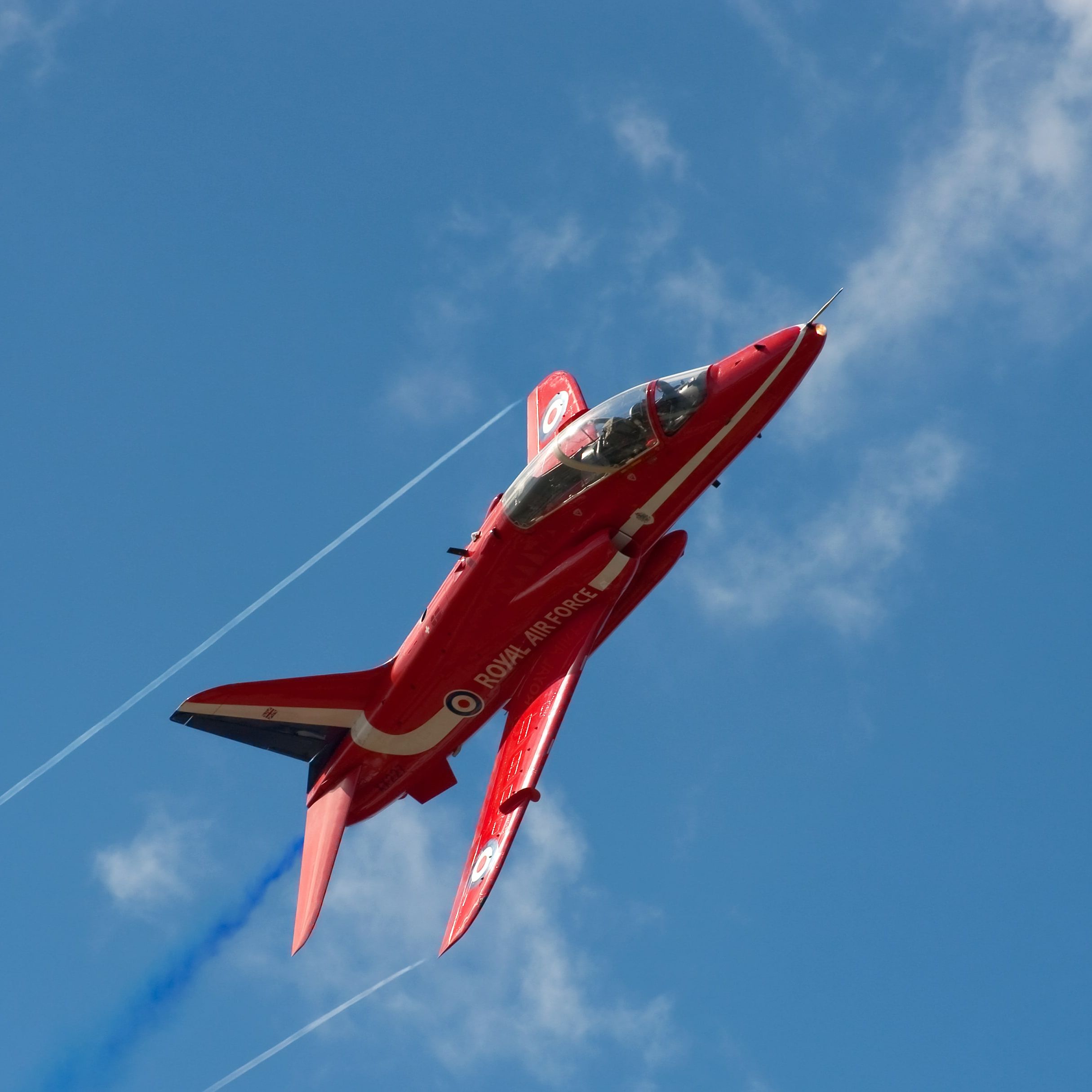 Red Royal Air Force jet performing aerial maneuver against a blue sky