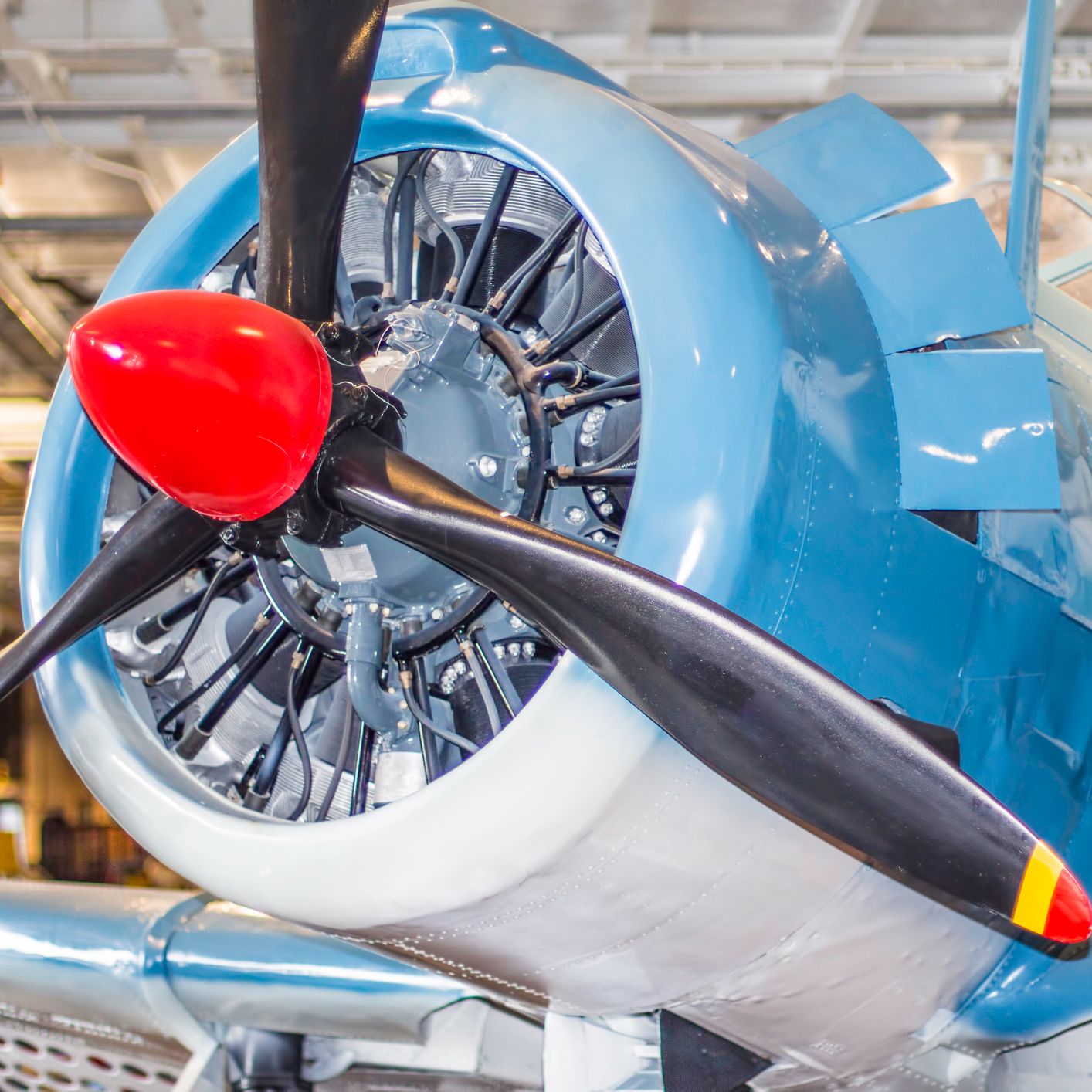 Close-up view of a vintage blue aircraft's propeller and engine inside a museum.